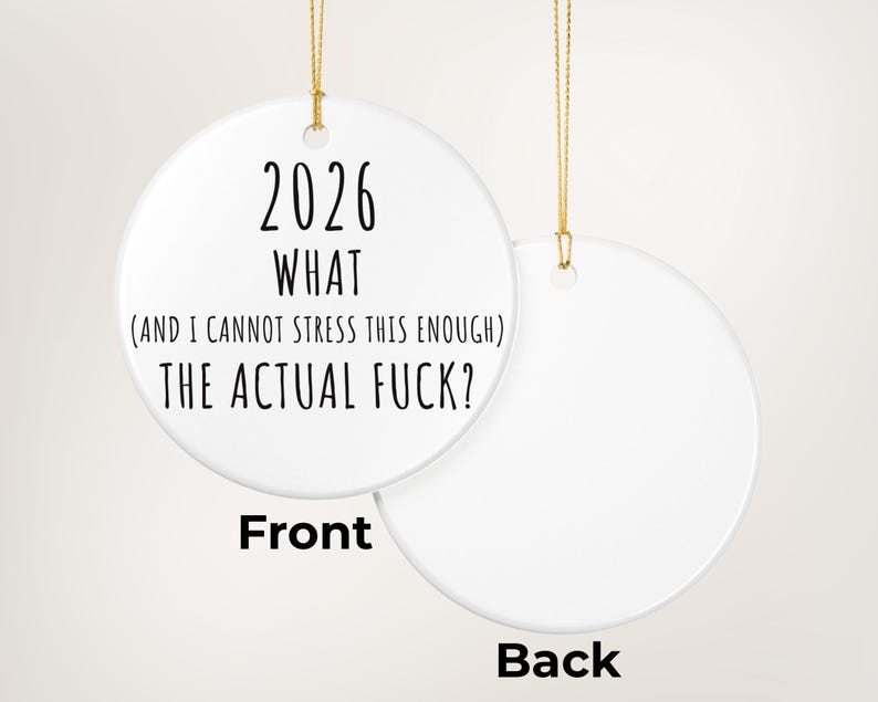 May include: A white ceramic Christmas ornament with gold string. The front of the ornament has the text "2026 WHAT (AND I CANNOT STRESS THIS ENOUGH) THE ACTUAL FUCK?". The back of the ornament is blank and labeled "Back".