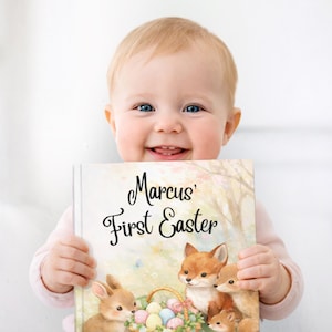 May include: A smiling baby holds a book titled "Marcus' First Easter." The book cover features watercolour illustrations of a bunny, foxes, and a basket of Easter eggs. The background is a soft, pastel-coloured scene.