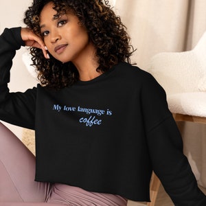 May include: A black cropped sweatshirt with the text "My love language is coffee" in blue lettering.