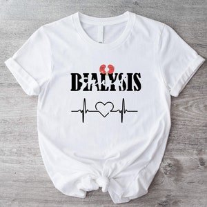 Pode incluir: Camiseta branca com texto preto que diz "Dialysis" com um gráfico de rim vermelho e uma linha de batimento cardíaco preto.