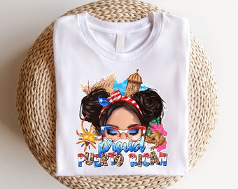 Puede incluir: Camiseta blanca con una ilustración colorida de una mujer con una diadema de bandera puertorriqueña, gafas de sol y un fondo festivo. El texto "Proud Puerto Rican" está impreso debajo de la ilustración.
