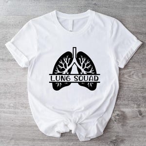 Op de afbeelding: Wit T-shirt met een zwarte afbeelding van longen en de tekst "LUNG SQUAD" erop gedrukt.