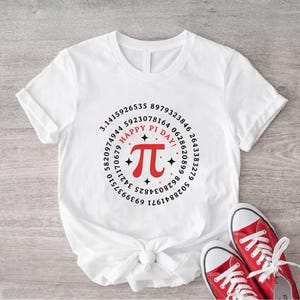 Könnte beinhalten: Weißes T-Shirt mit einer rot-schwarzen Grafik zum Tag des Pi. Das Design enthält das Pi-Symbol, den Satz "Happy Pi Day!" und eine kreisförmige Anordnung von Zahlen. Rote Leinenschuhe mit weißen Schnürsenkeln befinden sich unten.
