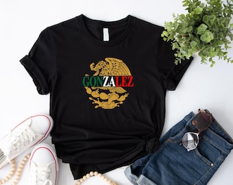 May include: Black t-shirt with a gold Mexican eagle design and the text "GONZALEZ" in a red, white, and green color scheme.