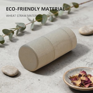 Peut inclure: Un récipient cylindrique en paille de blé beige avec une finition mate et lisse. Le texte "ECO-FRIENDLY MATERIAL" et "WHEAT STRAW MATERIAL" est imprimé en noir au-dessus de l'objet.