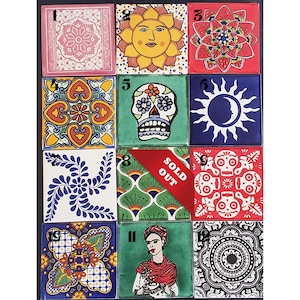 May include: Twelve colorful ceramic tiles with various designs, including a skull, sun, and floral patterns. Some tiles are marked with numbers 1 through 12. One tile is marked "SOLD OUT".