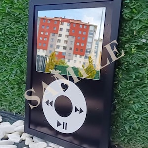 May include: Black framed mirror with a white graphic of a music player's control buttons. The mirror reflects a building with red and white walls. The word "SAMPLE" is printed on the mirror.