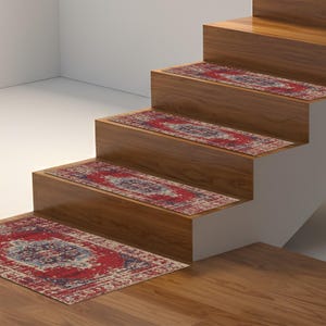 Może przedstawiać: Drewniane schody z czerwono-niebieskimi stopniami. Stopnie mają postarzany, zabytkowy wzór dywanu. Schody wykonane są z jasnobrązowego drewna i znajdują się w dobrze oświetlonym pomieszczeniu.