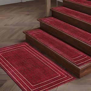 May include: Red stair treads and a matching rectangular rug with a detailed pattern. The treads are installed on wooden stairs. The rug and treads have a border design with a repeating pattern of small shapes.
