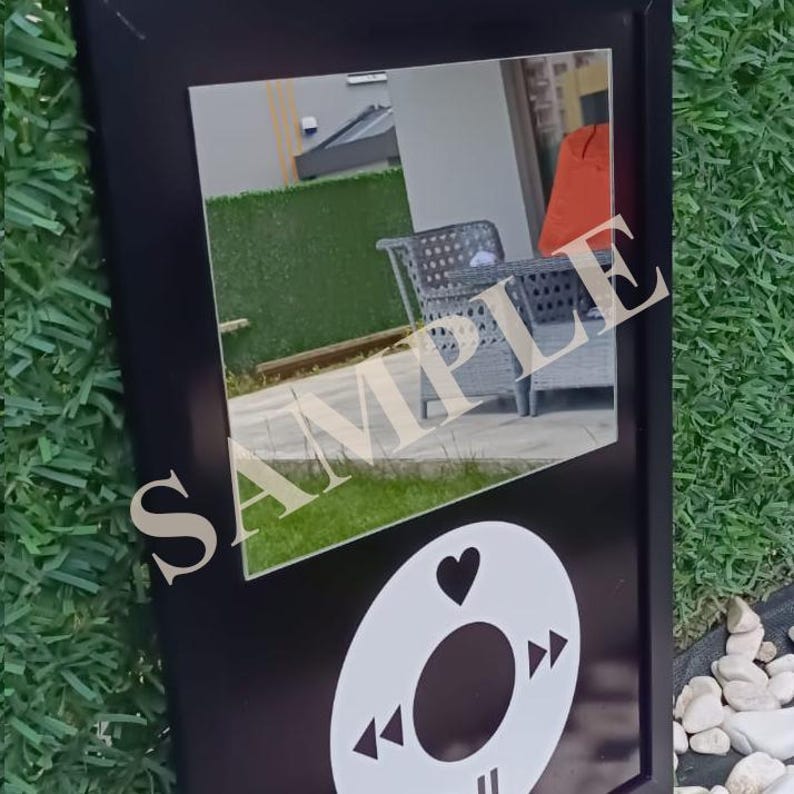 May include: Black framed mirror with a white graphic of a music player's control buttons. The mirror reflects an outdoor scene with patio furniture and the word "SAMPLE" overlaid on the mirror's surface.