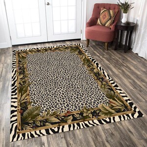May include: A beige and black area rug with a leopard print centre and a zebra print border. The border also features a floral design with green leaves and brown stems.