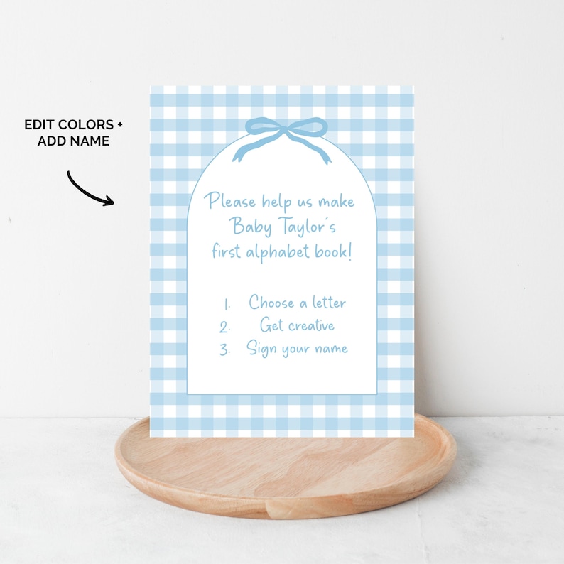 May include: A baby shower invitation with a blue gingham pattern background. The invitation reads "Please help us make Baby Taylor's first alphabet book!" with instructions to choose a letter, get creative, and sign your name.