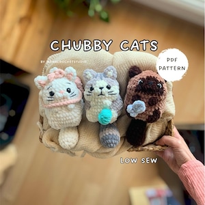 Puede incluir: Tres juguetes de gato de ganchillo hechos a mano en una cesta. Los gatos son blancos, grises y marrones, con acentos rosas, azules y grises. El texto "CHUBBY CATS" y "PDF PATTERN" son visibles. La frase "LOW SEW" también es visible.