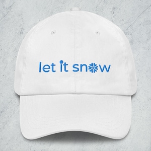 May include: A white baseball cap with a curved peak. The cap displays the blue text "let it snow" across the front, with a snowflake graphic replacing the letter "o". The cap is made of a soft material.