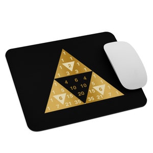 May include: A black mouse pad with a gold triangle design. The triangle features numbers in a pattern. The numbers are 1, 1, 1, 1, 2, 1, 1, 3, 3, 1, 1, 4, 6, 4, 1, 1, 5, 10, 10, 5, 1, 6, 15, 20, 15, 6, 1, 7, 21, 35, 35, 21, 7, 1, 1.