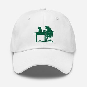 Può includere: Cappellino da baseball bianco con un design ricamato verde di una scimmia seduta a una scrivania che usa un computer.