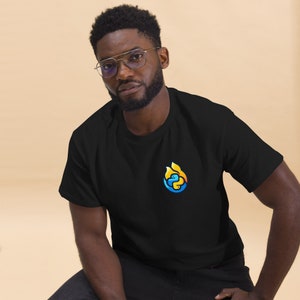 Peut inclure: Un t-shirt noir avec un logo bleu et jaune d'un serpent dans une flamme sur le devant.