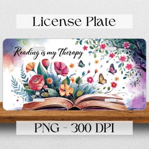 Op de afbeelding: Een wit kenteken met een aquarelontwerp van een open boek met bloemen en vlinders. De tekst "Reading is my Therapy" staat op het boek.