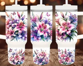 May include: Three white stainless steel tumblers with lids and straws. Each tumbler features a watercolor design of pink and purple lilies with green leaves and butterflies. The tumblers are on a wooden surface.