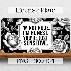 May include: Black and white license plate with a floral design and the text "I'M NOT RUDE. I'M HONEST. YOU'RE JUST SENSITIVE."