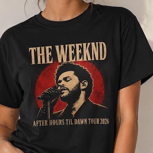 May include: A black short-sleeve t-shirt featuring a graphic print of The Weeknd singing into a microphone. The design includes a red circular background, the text THE WEEKND at the top, and the text AFTER HOURS TIL DAWN TOUR 2026 at the bottom.