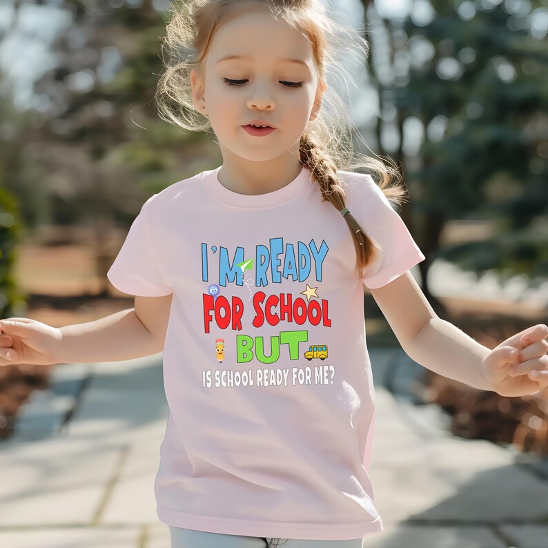 light pink kids crewneck t-shirt that reads “I’m ready for school but is school ready for me?” in colorful letters with fun icons.