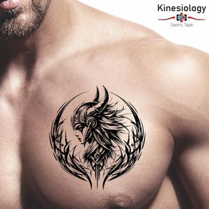 Può includere: Un tatuaggio temporaneo in bianco e nero raffigurante una guerriera con un elmo cornuto, all'interno di un disegno circolare. Il tatuaggio è applicato sul petto. L'immagine include anche il testo "Kinesiology Sports Tape".
