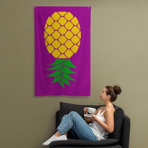 May include: A purple wall tapestry with a large yellow pineapple design. The pineapple has a green stem and leaves.