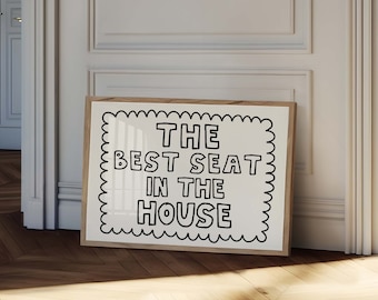 May include: A framed print with a white background and black text that reads "THE BEST SEAT IN THE HOUSE" in a playful, oversized font.