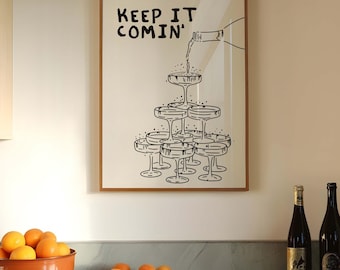 Peut inclure: Une impression encadrée avec une illustration en noir et blanc d'une bouteille de champagne se versant dans une pyramide de flûtes à champagne. L'impression porte le texte "Keep it comin'" en haut. L'impression est accrochée à un mur dans une cuisine avec un plan de travail en marbre et un bol d'oranges.