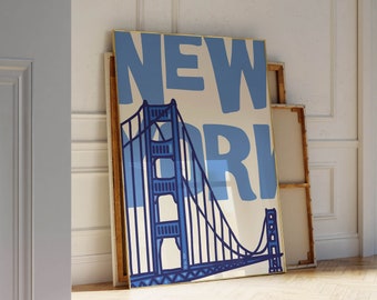 Puede incluir: Un póster enmarcado con un diseño azul y blanco que presenta el texto "NEW YORK" y una imagen estilizada del Puente Golden Gate.