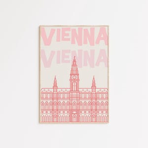 May include: Pink and beige art print featuring the word "VIENNA" in a bold font above a detailed line drawing of a building. The building has a tall central tower and multiple smaller towers.