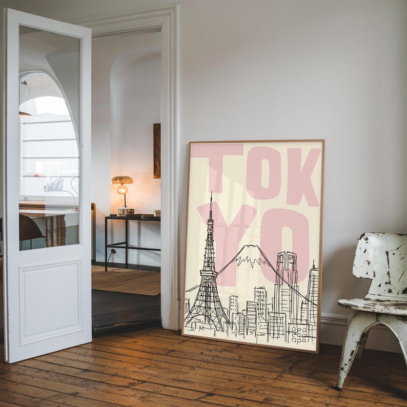 May include: A framed art print featuring a black and white line drawing of the Tokyo skyline, including the Tokyo Tower and Mount Fuji. The word "TOKYO" is printed in large pink letters over a cream-colored background.