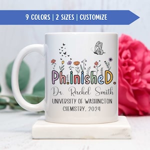 May include: White ceramic coffee mug featuring a colourful "Phinished." design, a butterfly, and flowers. The text "Dr. Rachel Smith, University of Washington, Chemistry, 2024" is printed below the design.