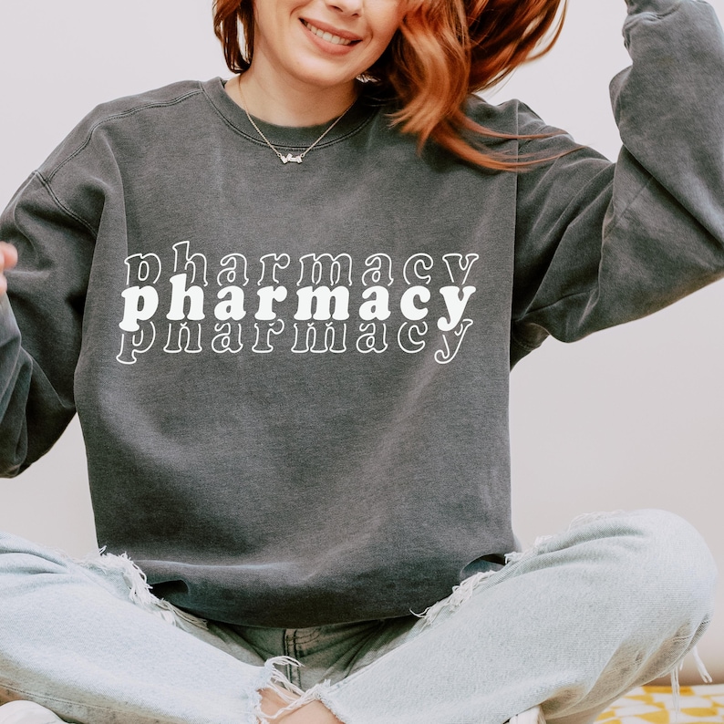 May include: A dark gray sweatshirt with the word "pharmacy" printed three times in white, with each word slightly offset from the one above it.