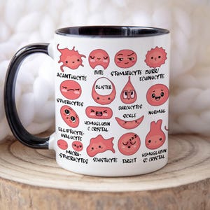 May include: White ceramic mug with a black handle and rim, featuring illustrations of various blood cell types in shades of pink and red. The mug includes labels such as "Acanthocyte" and "Normal".