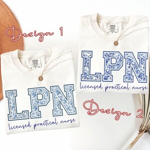 May include: Two off-white Comfort Colors t-shirts with the letters "LPN" in a blue floral design. The text "licensed practical nurse" is below the letters. Each shirt has a gold necklace. The words "Design 1" and "Design 2" are written in cursive.