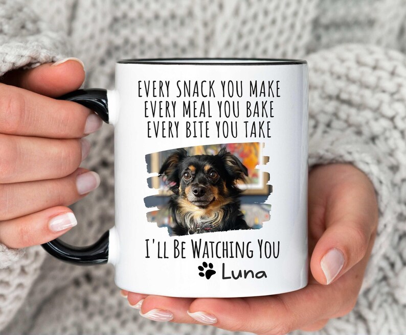 May include: White ceramic mug with a black rim and handle. The mug features a photo of a small black and brown dog with the text "EVERY SNACK YOU MAKE EVERY MEAL YOU BAKE EVERY BITE YOU TAKE I'LL BE WATCHING YOU Luna".