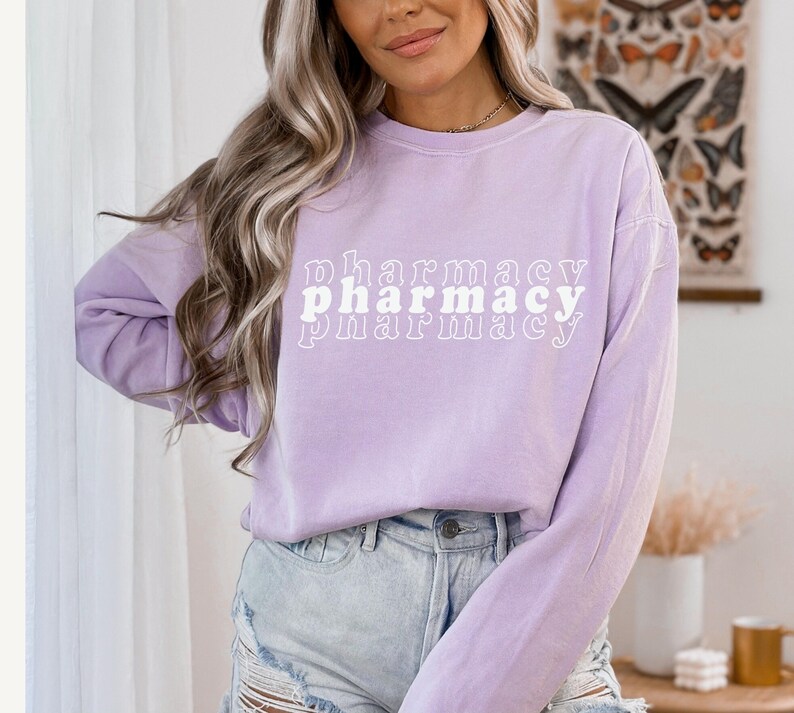 May include: A lavender long-sleeve shirt with the text "pharmacy" printed in white in a retro font.