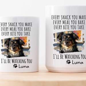 May include: Two white ceramic mugs with black text and a paw print. The text reads "Every snack you make, every meal you bake, every bite you take, I'll be watching you, Luna". Each mug features a photo of a brown and black dog.