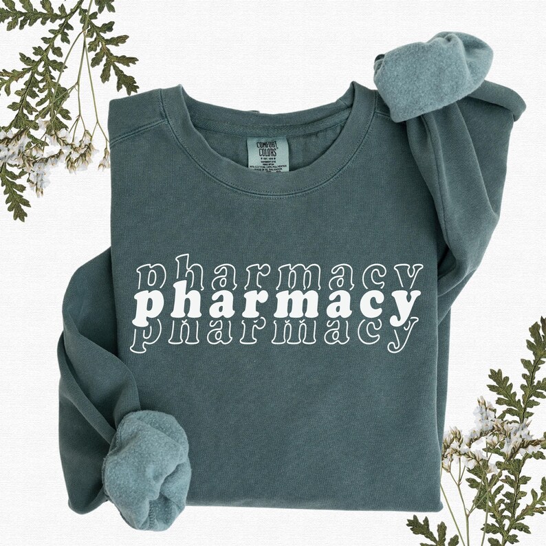 May include: A teal blue sweatshirt with the word "pharmacy" written in white, stacked three times with each word slightly offset from the one above it.
