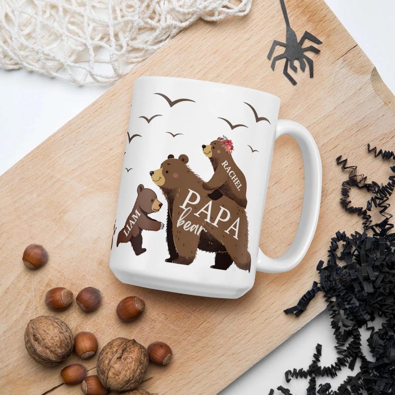 Może przedstawiać: Biały kubek ceramiczny z wzorem rodziny brązowych niedźwiedzi. Niedźwiedź tata jest oznaczony jako "Papa Bear", a niedźwiedź mama jako "Rachel". Mały niedźwiedź jest oznaczony jako "Liam".