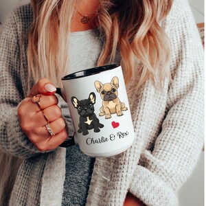 May include: White ceramic mug with a black rim and handle. The mug features a cartoon image of two French Bulldogs, one black and one tan, with a red heart between them. The text "Charlie & Rex" is printed below the dogs.