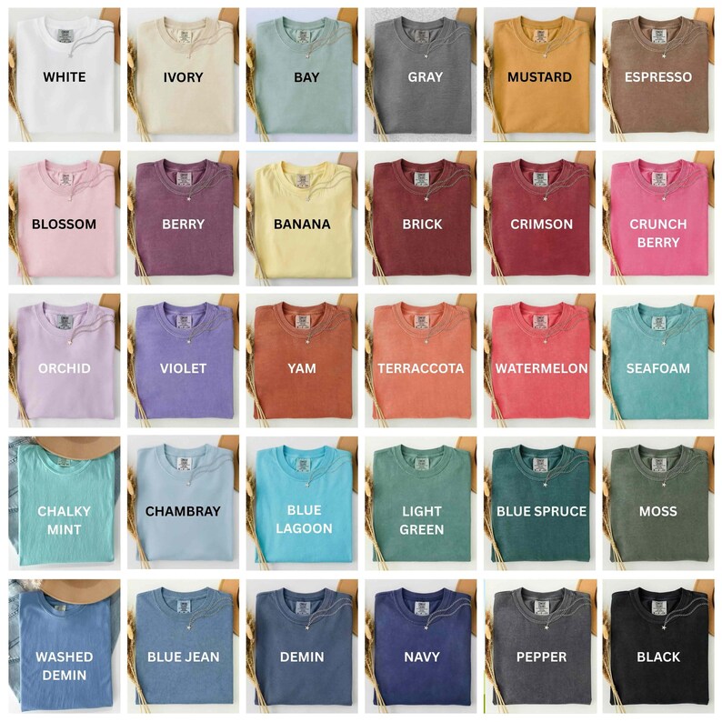Op de afbeelding: Een verzameling gevouwen t-shirts in verschillende kleuren, waaronder wit, ivoor, baai, grijs, mosterd, espresso, bloesem, bes, banaan, baksteen, karmozijn, crunch berry, orchidee, violet, yam, terracotta, watermeloen, schuim, krijtachtige munt, chambray, blauwe lagune, lichtgroen, blauwe spar, mos, gewassen demin, blauwe spijkerbroek, demin, marine, peper en zwart.