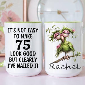 May include: Two white ceramic mugs with light green handles and interior rims. One mug features the black text: IT'S NOT EASY TO MAKE 75 LOOK GOOD BUT CLEARLY I'VE NAILED IT. The other mug shows a green bird wearing pink glasses and the name Rachel.