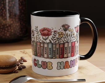 Puede incluir: Taza de cerámica blanca con borde y asa negros. La taza presenta un diseño de libros apilados con flores que crecen desde la parte superior. El texto "CLUB NAME" está impreso en letras de colores en la parte inferior de la taza.