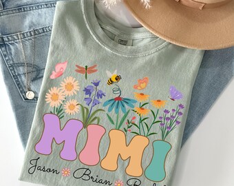 May include: Sage green t-shirt with a floral design and the word "MIMI" in colorful, retro-style letters. The design includes flowers, butterflies, and the names Jason, Brian, and Rachel.
