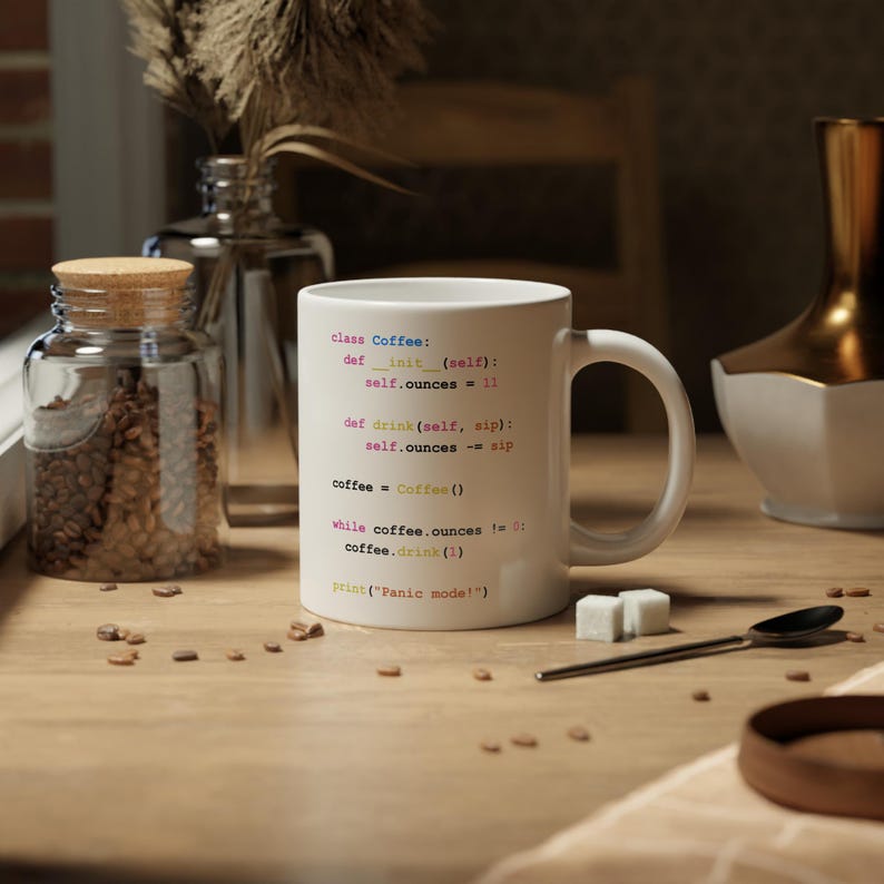 May include: White ceramic coffee mug with a humorous coding joke printed on it. The code is written in a light pink, yellow, and blue font. The code reads: "class Coffee: def __init__(self): self.ounces = 11 def drink(self, sip): self.ounces -= sip coffee = Coffee() while coffee.ounces != 0: coffee.drink(1) print('Panic mode!)"