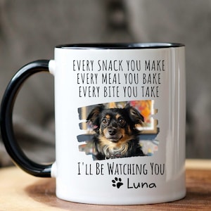 May include: White ceramic mug with a black rim and handle. The mug features a black and white photo of a dog with the text "EVERY SNACK YOU MAKE EVERY MEAL YOU BAKE EVERY BITE YOU TAKE I'LL BE WATCHING YOU Luna".