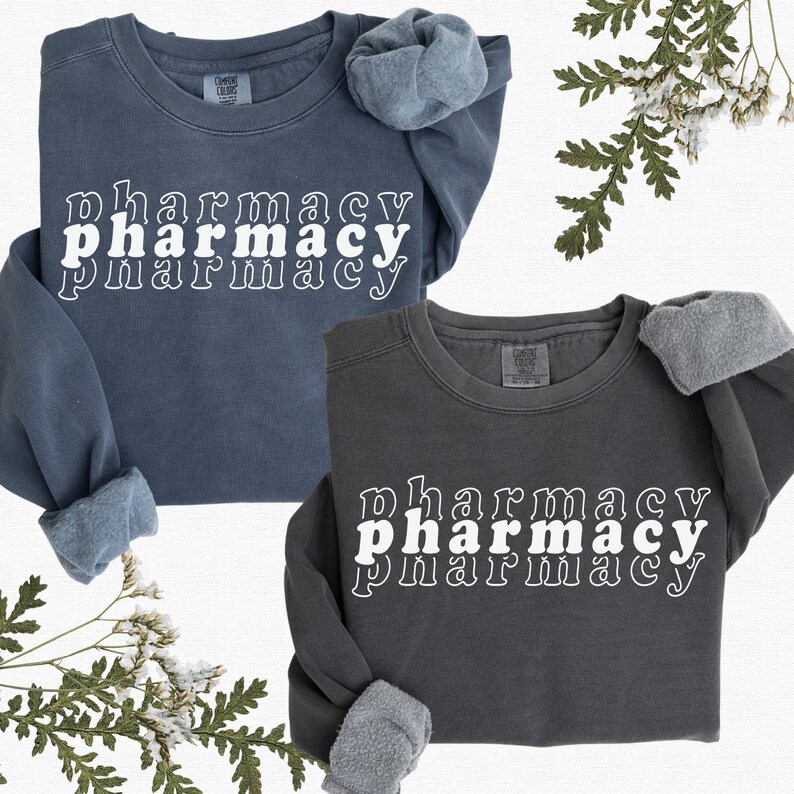 May include: Two sweatshirts with the word "pharmacy" printed on them in a retro style. The sweatshirts are in different shades of blue and gray.